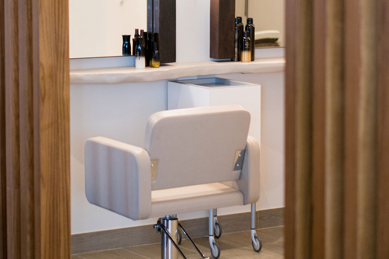 White salon chair on front of a mirror.