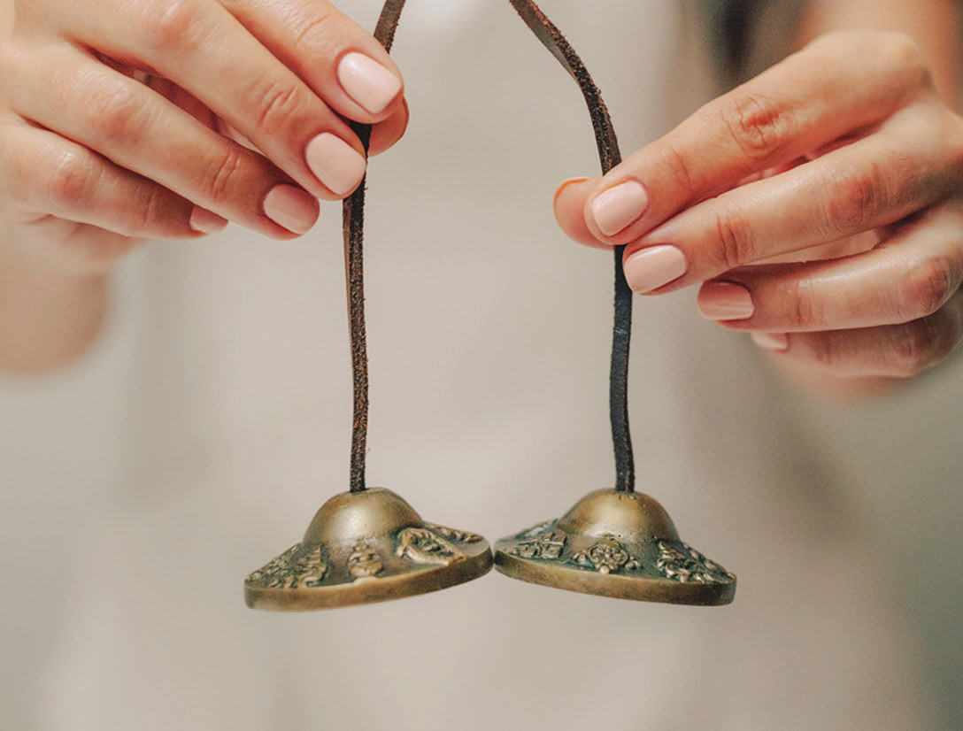 Hands holding a set of tshinga bells.