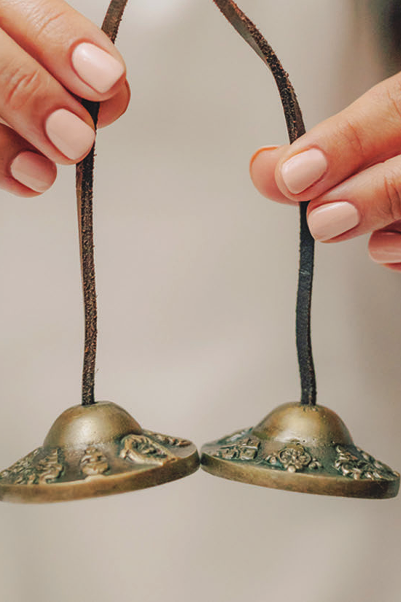 Hands holding a set of tshinga bells.