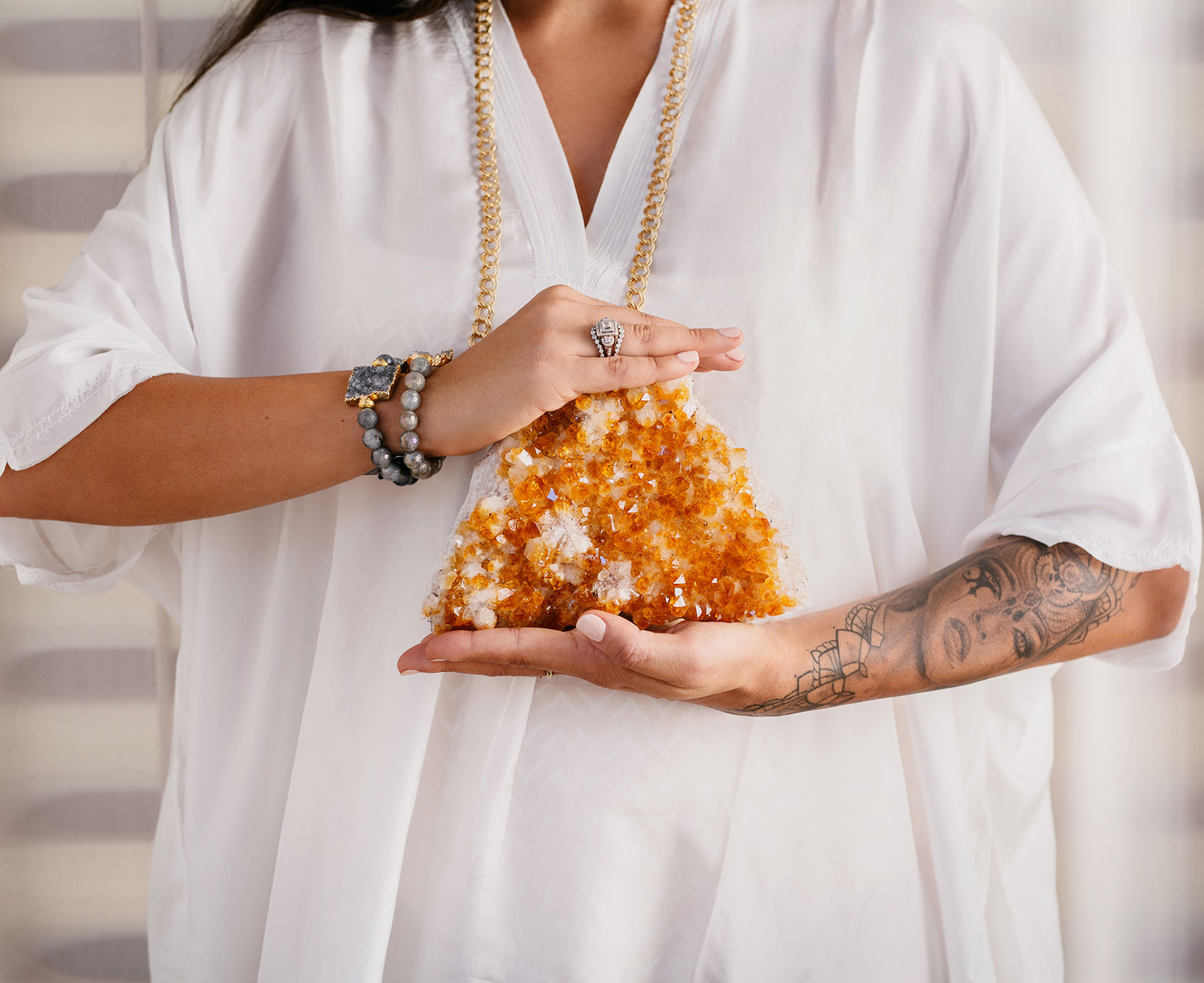 Woman dressed in white holding a large geode.