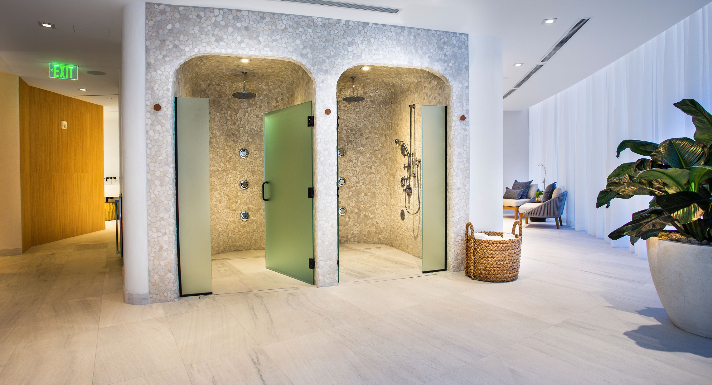 Locker room of luxury spa showing two tile showers with frosted glass doors.