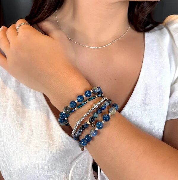 womans arm showing multiple blue beaded bracelets